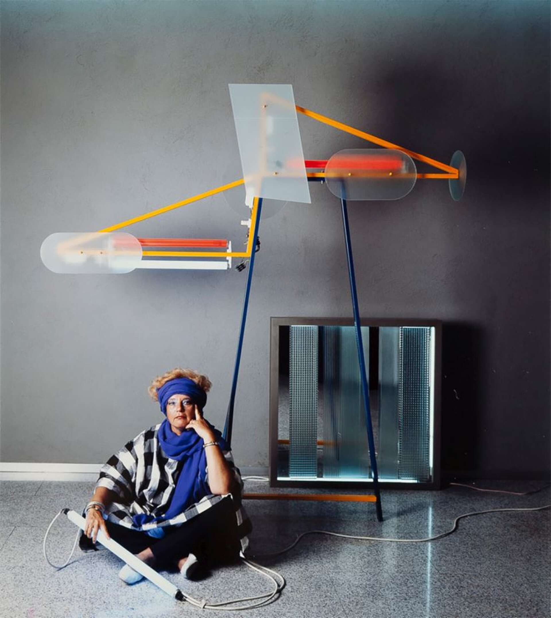 Woman is sitting in front of a art installation