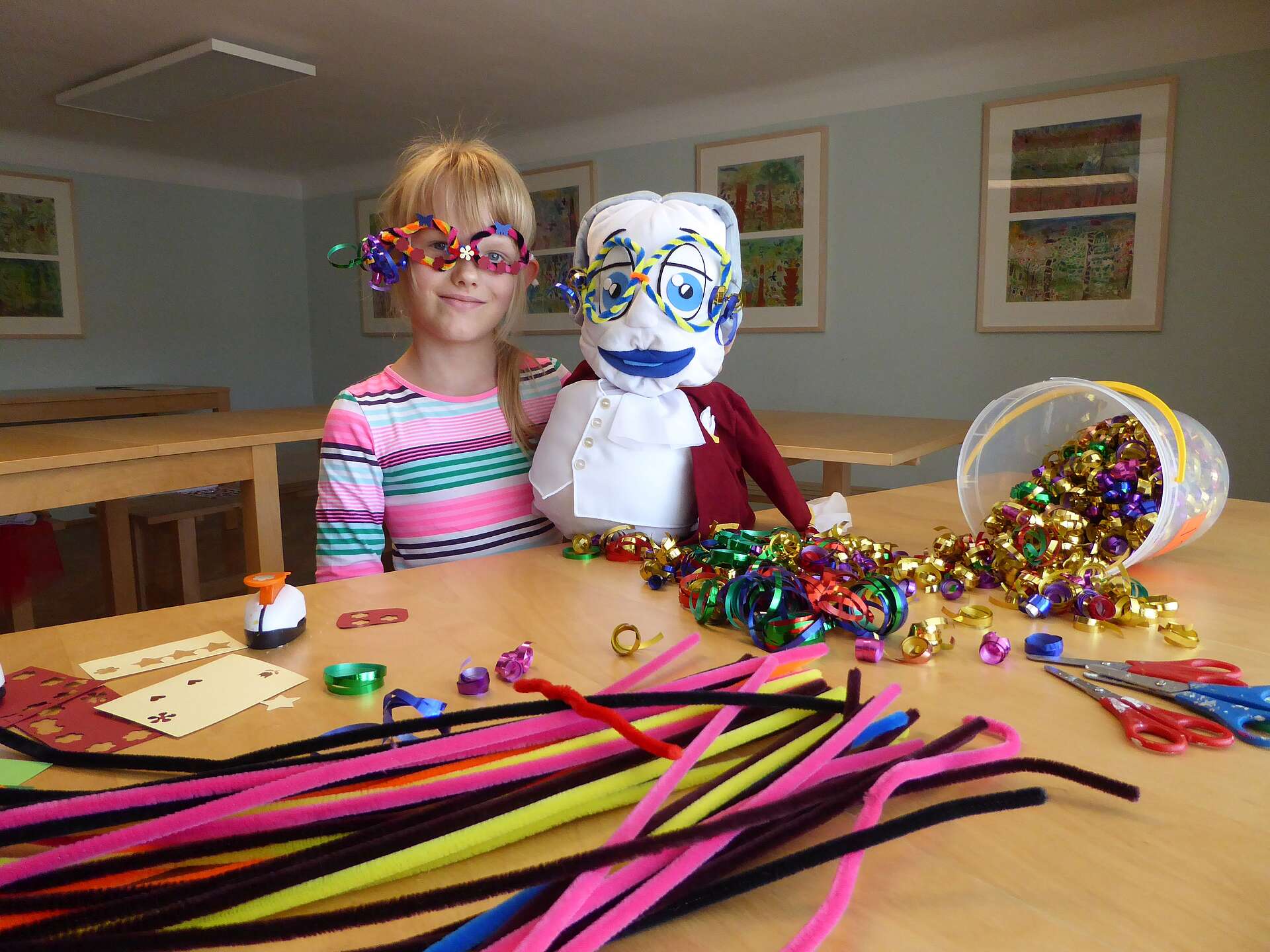 Mädchen sitzt neben Maskottchen Poldi und trägt eine selbstgemachte Faschingsbrille
